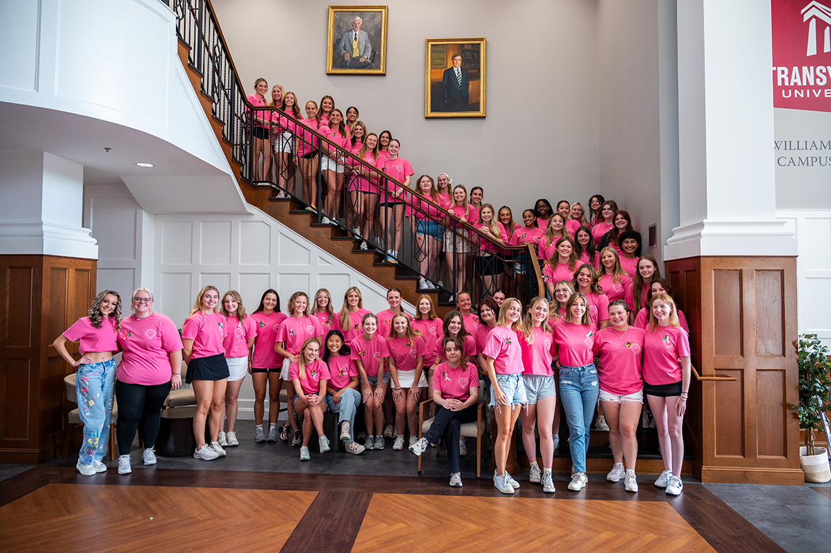 students posing for a photo around stairs