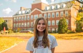 student in front of a campus building