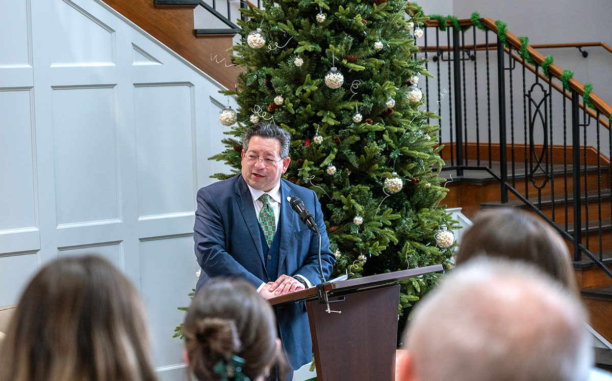 person at a podium in front of a Christmas tree