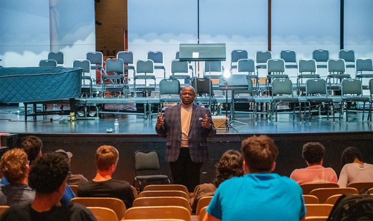 Person talking to students in front of a stage